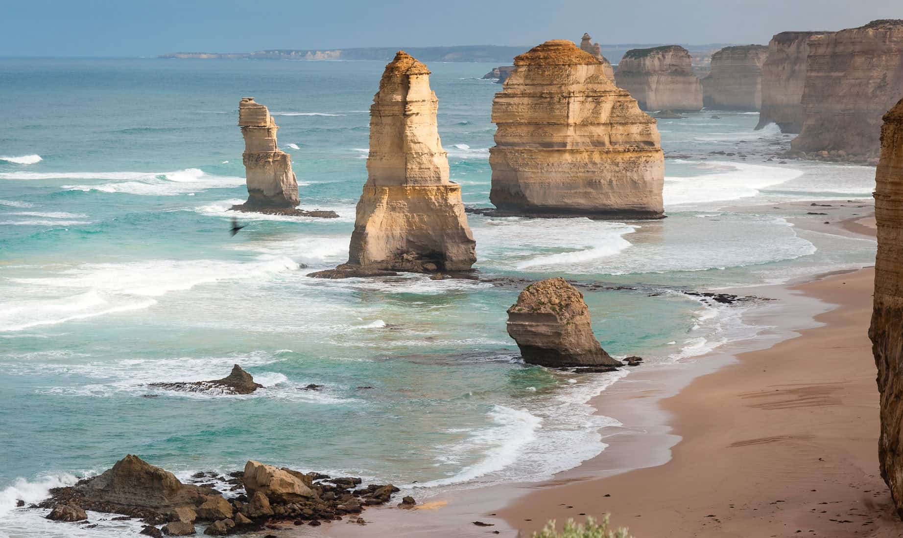 View of the twelve apostles limestone stacks off the coast of victoria, australia, with waves crashing against the shore.