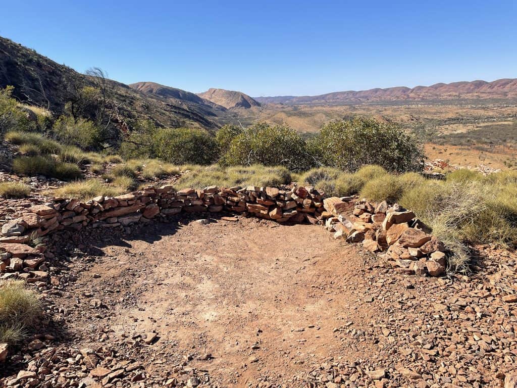 Typical primitive Campsite on the Larapinta Trail. Cleared pad on red dirt with a low rock wall