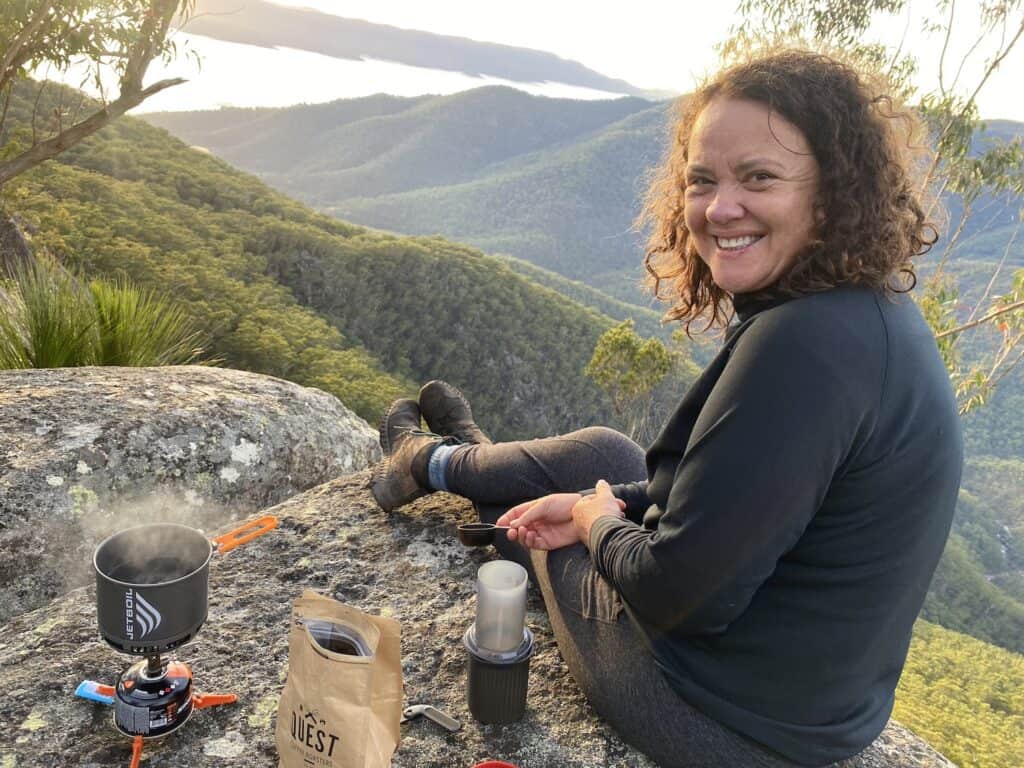 Woman sitting on the ledge, making a coffee with sunrise