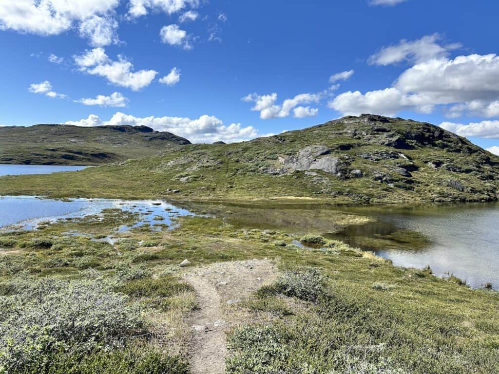 Two overflowing lakes are joined - with green hills and blue sky