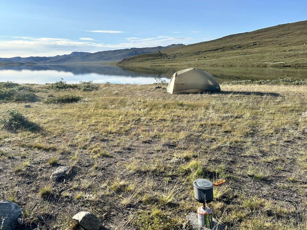 Lake with tent and camping stove on the shores