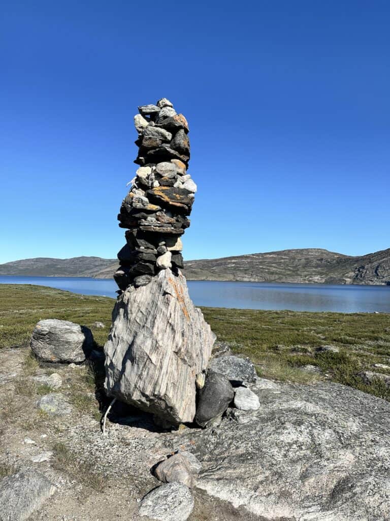 rock cairn on the arctic circle trail with a lake in the distance